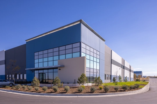 an angled view of an industrial building showing the main corner entrance with a cantilever overhang above the door